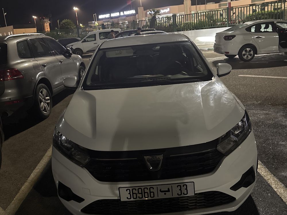 White Dacia Sandero hatchback at a night handover at Agadir airport